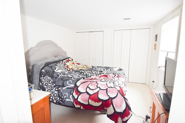 bedroom with carpet flooring and multiple closets