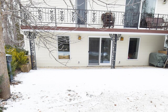 snow covered back of property with a balcony