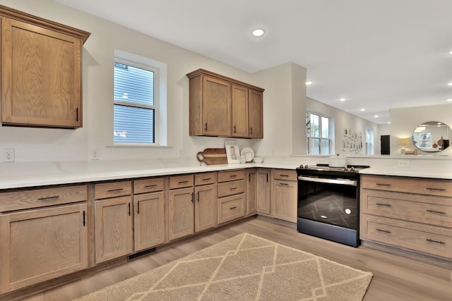 kitchen with black range with electric stovetop and light hardwood / wood-style flooring