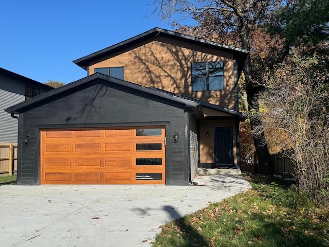 modern home with fence, driveway, and a garage