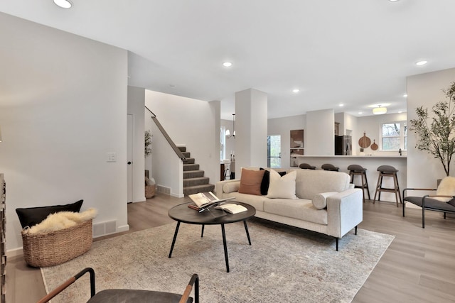 living area featuring a wealth of natural light, stairway, visible vents, and light wood-style flooring