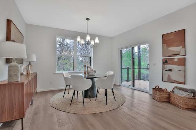 dining area with light wood-style flooring, a notable chandelier, and plenty of natural light