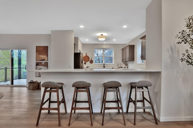 kitchen with a peninsula, a kitchen breakfast bar, light countertops, and freestanding refrigerator