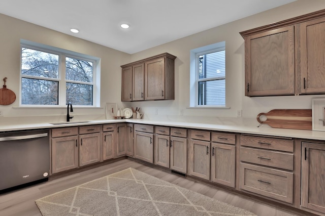 kitchen featuring recessed lighting, stainless steel dishwasher, a sink, and light wood-style flooring