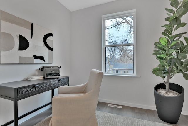 office space featuring baseboards, wood finished floors, visible vents, and a wealth of natural light