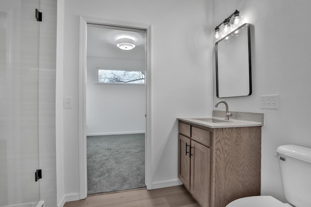 bathroom featuring baseboards, wood finished floors, vanity, and toilet