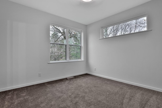 spare room with baseboards and dark colored carpet