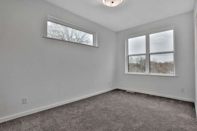 unfurnished room featuring dark colored carpet and baseboards