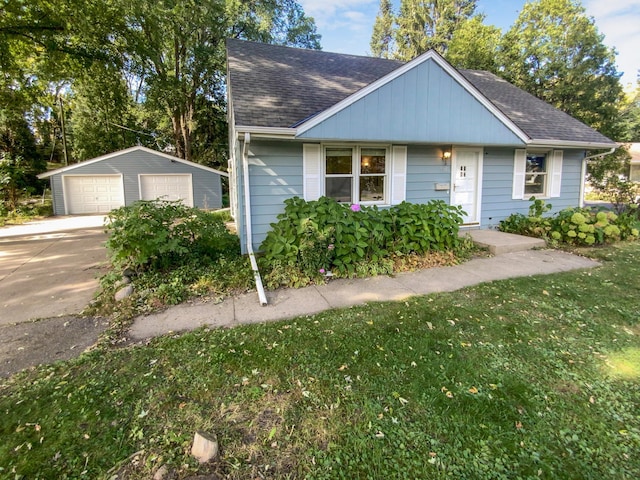 view of front of home with a front yard, a garage, and an outbuilding