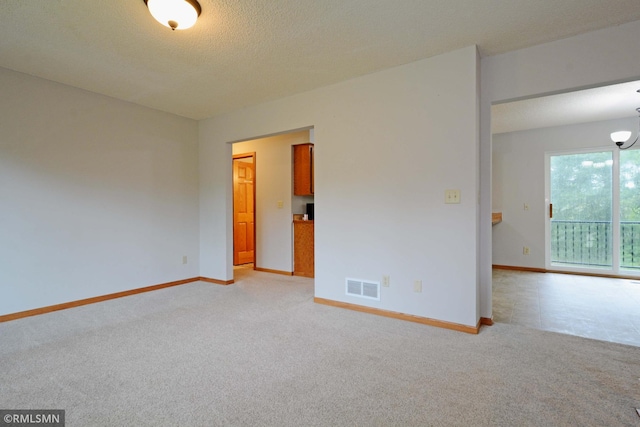 carpeted empty room featuring a textured ceiling