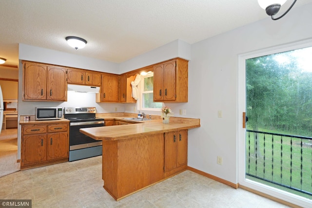 kitchen with sink, stainless steel appliances, kitchen peninsula, and a healthy amount of sunlight