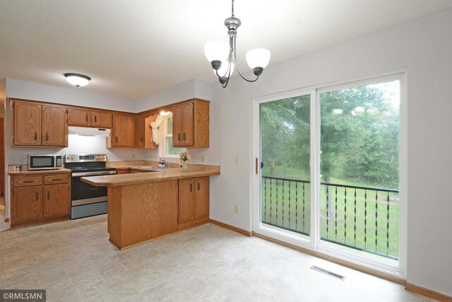 kitchen featuring appliances with stainless steel finishes, hanging light fixtures, kitchen peninsula, an inviting chandelier, and sink