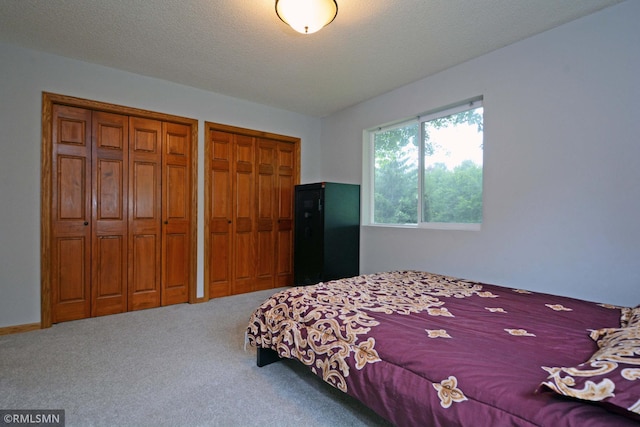 bedroom featuring a textured ceiling, multiple closets, and carpet floors