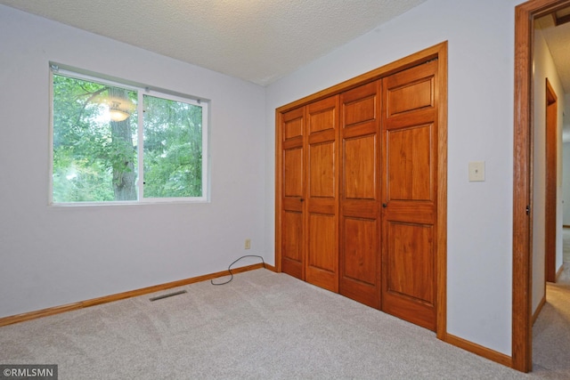 unfurnished bedroom featuring carpet floors, a textured ceiling, and a closet