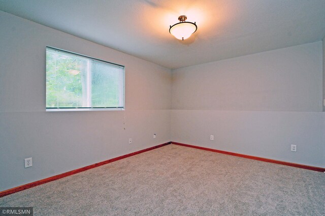 carpeted empty room with lofted ceiling