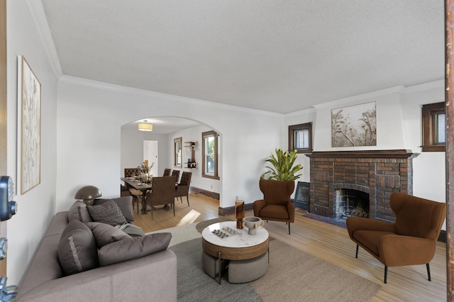 living room featuring ornamental molding, a brick fireplace, and light hardwood / wood-style floors