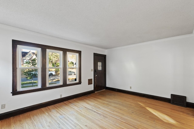 empty room with a textured ceiling and light wood-type flooring