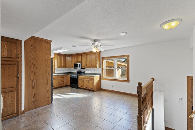 kitchen featuring a textured ceiling, light tile patterned flooring, black range oven, and ceiling fan