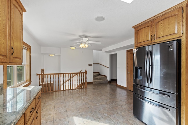 kitchen featuring ceiling fan, light stone counters, light tile patterned floors, and stainless steel refrigerator with ice dispenser