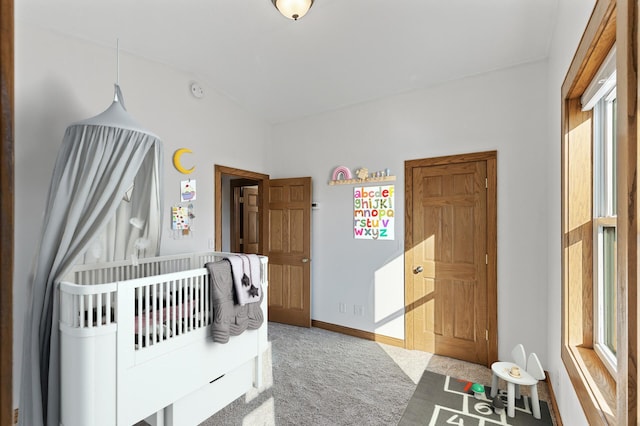 bedroom with multiple windows, a nursery area, and carpet floors