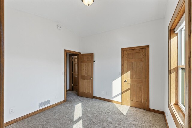 unfurnished bedroom with lofted ceiling, carpet, and multiple windows