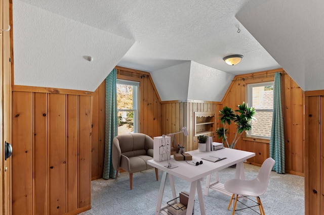 carpeted office space with lofted ceiling, a healthy amount of sunlight, and wooden walls