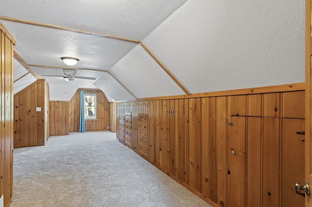 additional living space featuring wood walls, light colored carpet, and a textured ceiling