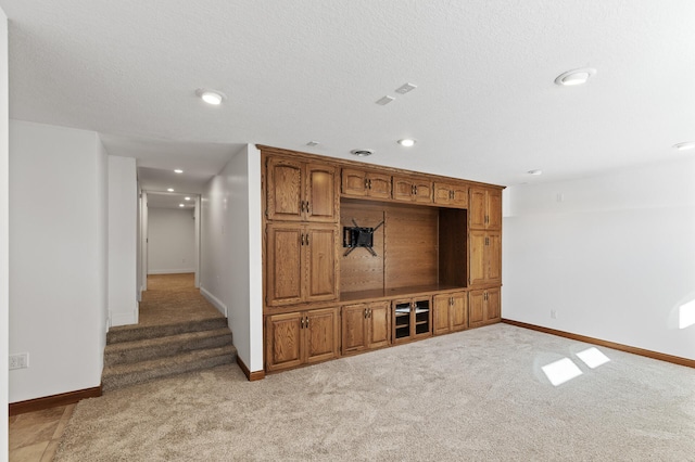 interior space with a textured ceiling and light colored carpet