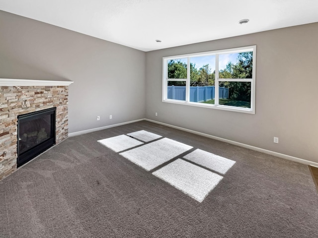 unfurnished living room with dark carpet and a fireplace