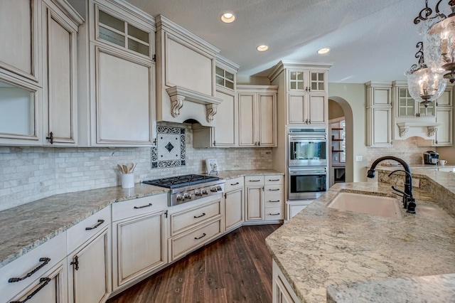 kitchen with stainless steel appliances, cream cabinets, sink, and decorative light fixtures