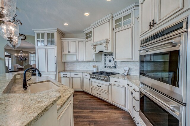 kitchen with light stone countertops, appliances with stainless steel finishes, pendant lighting, and dark hardwood / wood-style flooring