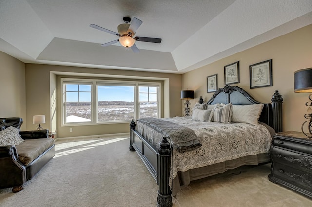 carpeted bedroom with ceiling fan and a tray ceiling