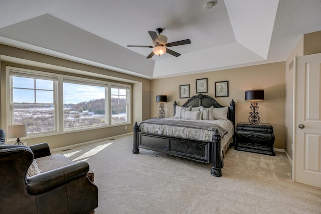 carpeted bedroom featuring ceiling fan and a tray ceiling