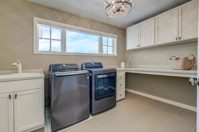 washroom featuring cabinets, an inviting chandelier, washing machine and clothes dryer, and a wealth of natural light