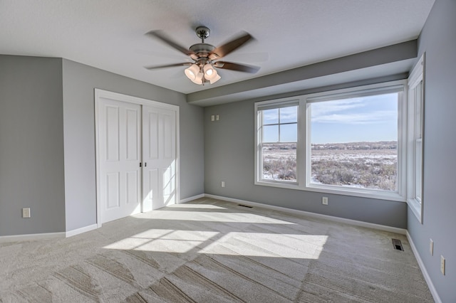 unfurnished bedroom with a closet, light colored carpet, and ceiling fan