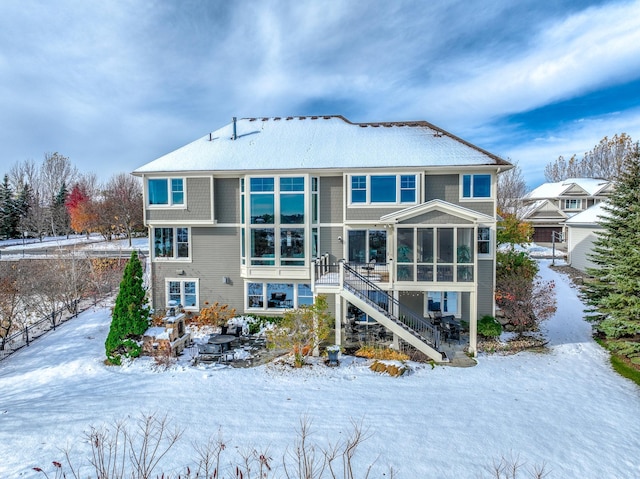 snow covered back of property with a sunroom