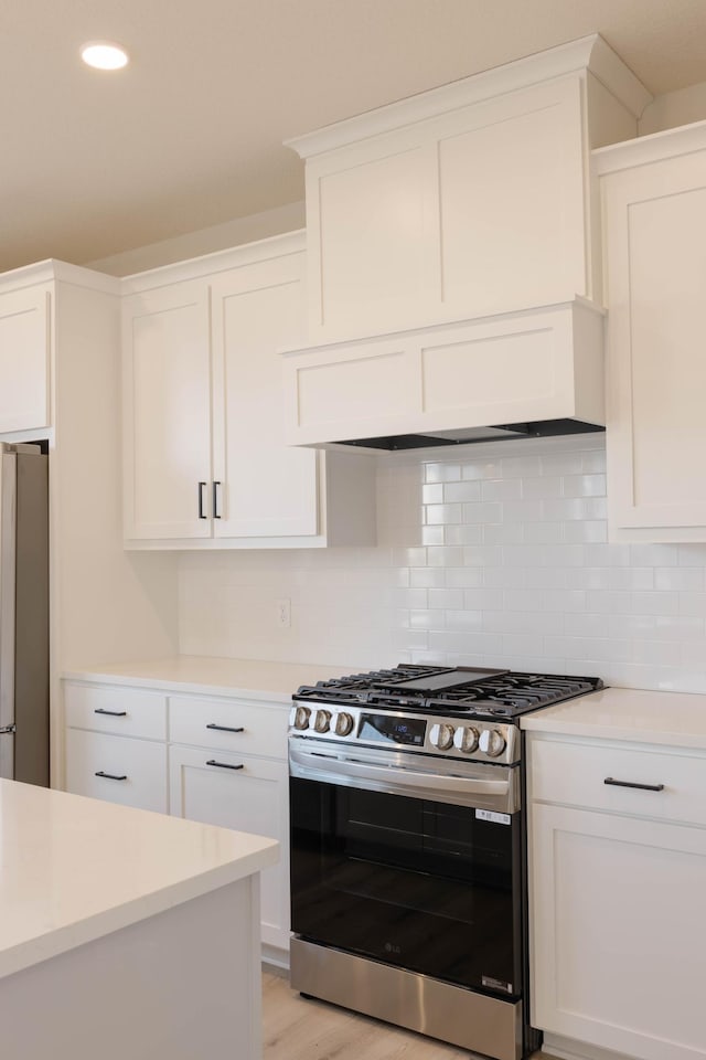 kitchen with premium range hood, decorative backsplash, light wood-type flooring, white cabinetry, and stainless steel appliances