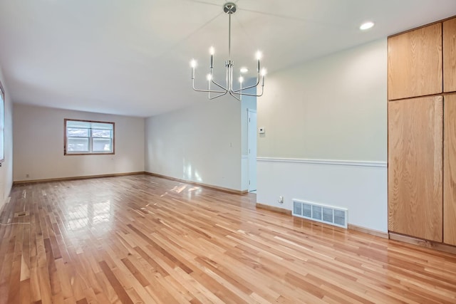 empty room with an inviting chandelier and light hardwood / wood-style floors