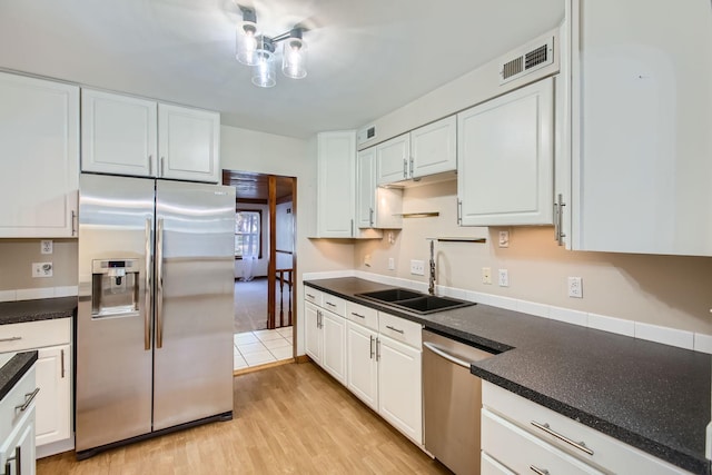 kitchen with appliances with stainless steel finishes, white cabinetry, and light hardwood / wood-style floors