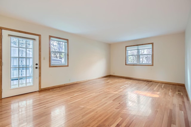 spare room with light hardwood / wood-style floors and plenty of natural light