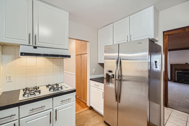 kitchen with stainless steel fridge, white cabinets, tasteful backsplash, light wood-type flooring, and white gas cooktop