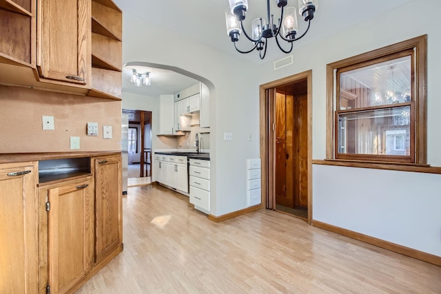 kitchen featuring light hardwood / wood-style flooring, white cabinets, a chandelier, and sink