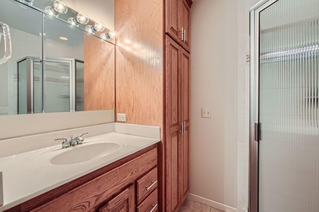 bathroom with a shower with door, vanity, and tile patterned floors