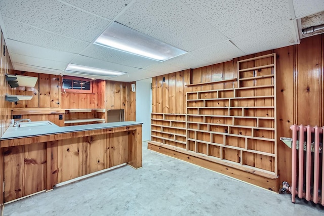 bar featuring a paneled ceiling, radiator heating unit, wooden walls, and light colored carpet