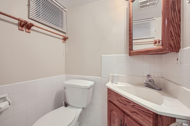 bathroom with tile walls, vanity, and toilet