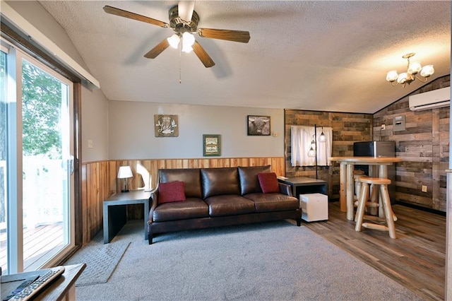 living room with lofted ceiling, a textured ceiling, wooden walls, ceiling fan with notable chandelier, and hardwood / wood-style floors