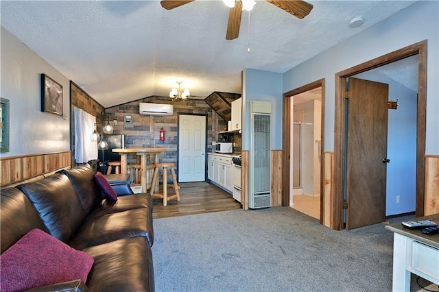 living area featuring wood walls, wainscoting, a wall mounted air conditioner, a textured ceiling, and vaulted ceiling
