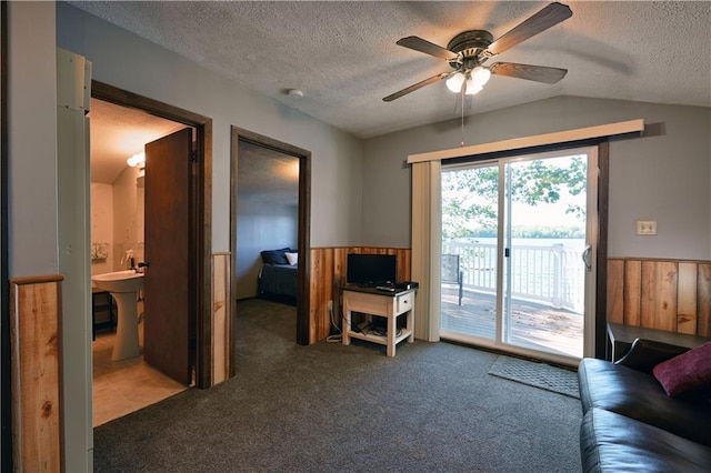 carpeted living room featuring a textured ceiling, vaulted ceiling, and ceiling fan