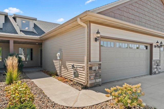 646 Shardlow Pl NE, Byron, MN 55920 - view of property exterior with a garage, a shingled roof, stone siding, and driveway