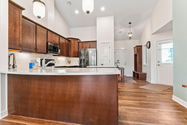 646 Shardlow Pl NE, Byron, MN 55920 - kitchen featuring light wood finished floors, a peninsula, vaulted ceiling, light countertops, and appliances with stainless steel finishes